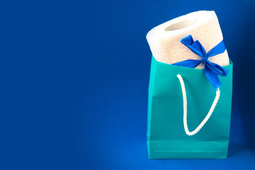 toilet paper roll with gift bow in pocket on blue background, copy space for the text