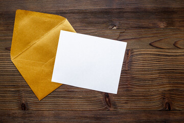 Blank white paper on the golden envelope. Mockup of letter or greeting card. Top view - 793866389