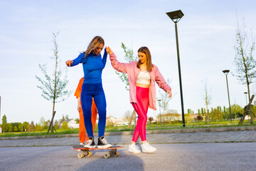 Ragazze in città che si divertono correndo sullo skateboard.