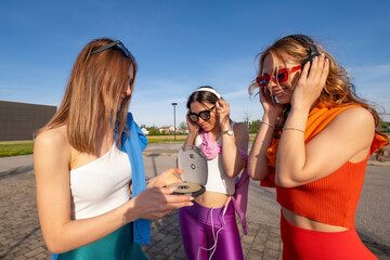 tre ragazze felici che ascoltano musica in esterna