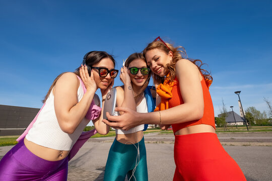 tre ragazze felici che ascoltano musica in esterna