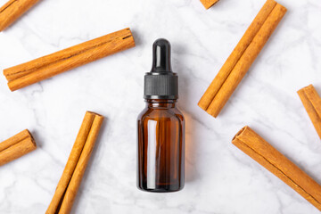 Cinnamon aromatic essential oil and cinnamon sticks on a wooden background. Aromatherapy. Organic cosmetic oil. Spa concept. Place for text. Copy space.