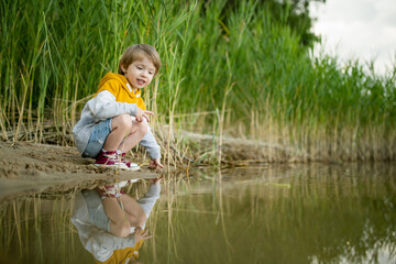 Cute little boy playing by a lake or river on hot summer day. Adorable child having fun outdoors during summer vacations. - 793871124