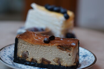 A piece of espresso macadamia cheese cake topped with coffee beans on the plate with blur of...
