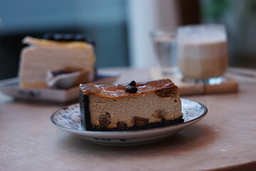 A piece of espresso macadamia cheese cake topped with coffee beans on the plate with blur of...