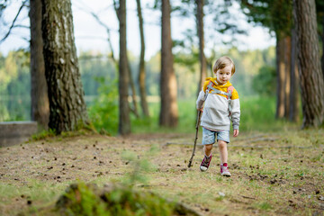 Cute little boy with a backpack having fun outdoors on sunny summer day. Child exploring nature. Kid going on a trip. - 793871353