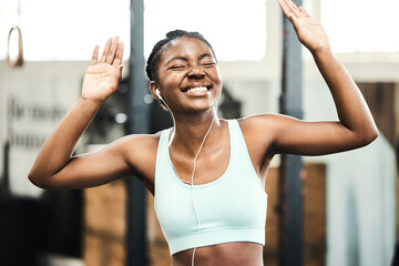 Earphones, healthy and black girl in gym, happy and listening for exercise, online and streaming on...