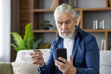 Senior man with credit card looking confused at smartphone