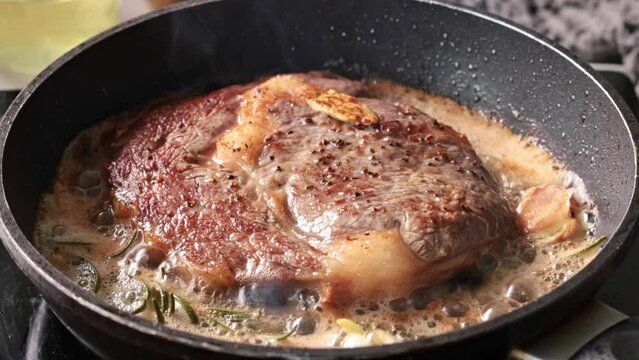 delicious juicy geef steak meat cooking on a pan with garlic and rosemary in melted butter. Process of making perfect steak at home