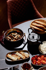 A sumptuous Turkish lunch, the menu of which presents a symphony of flavors. The menu includes bread, cheeses, sliced fresh fruits, pickled vegetables, snacks, hummus. Turkish tea in bowls.