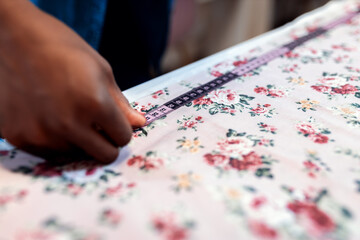 Close up of female fashion tailor hands working on the measurements for the dress design in her workshop.