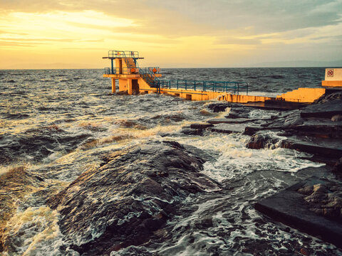 Blackrock diving board in Galway city, Ireland. Popular city landmark by the ocean with beautiful viewpoint on top. Travel and tourist hotspot. Sport and entertainment. Dramatic sunrise light.