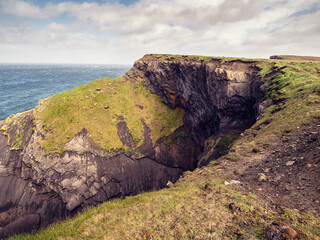 Kilkee cliff in county Clare, Ireland. Popular travel area with stunning nature scenery with green fields, ocean and dramatic sky. Irish landscape. Rough coast line. Warm sunny day.