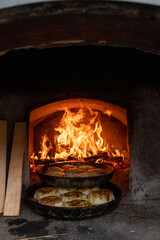 Sizzling flatbreads baking in a traditional stone oven, firewood ablaze, capturing the essence of...