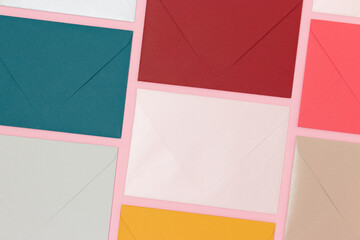 Multicolored envelopes neatly laid out on a pink background. Creative business concept.