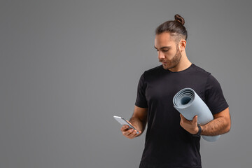 Man Holding Yoga Mat and Cell Phone