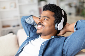 Black man enjoying music on headphones at home