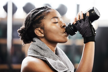 Active, black woman and fitness by drinking water in gym for health or energy from training or...
