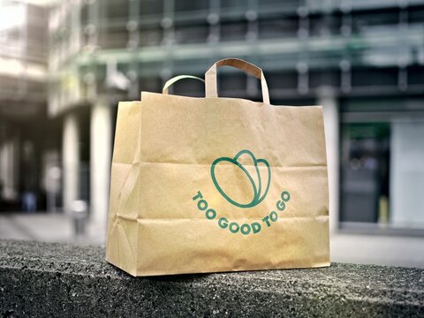 Ulm, Germany - April, 23, 2024: Paper Bag with almost expired food, saved from waste with Too Good To Go app. Zero waste grocery shopping via app fighting with throwing out food. 