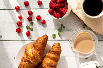 Cup of coffee and croissants and berries. on white wooden. breakfast. Morning.