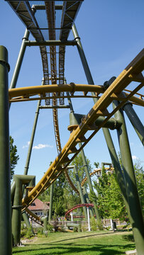Cleebronn, Germany-May 18.2023: Yellow-coloured roller coaster tracks and lifthill of the roller coaster "Hals-&uuml;ber-Kopf" in "Tripsdrill" intersect, with nature in the background