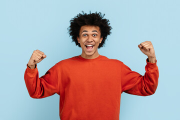 Black man celebrating with fists up on blue background