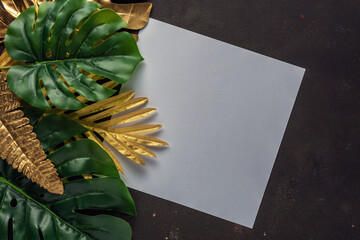 Creative layout with gold and green tropical palm leaves with white frame on black background....