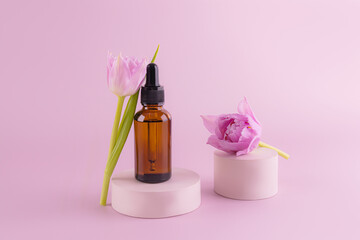 Fashion beauty product, serum in glass cosmetic bottle with dropper for face and body skin care standing on a round cement podium with a tulip flower.