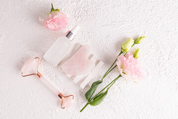 White matte bottle with natural remedy, serum, massage oil on white plaster embossed podium among flowers. Care concept.