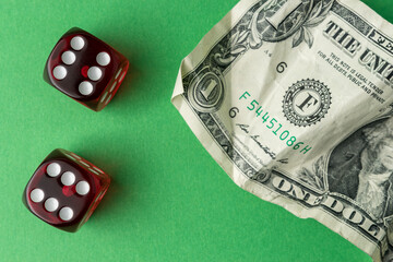Two red playing dices with one dollar bill on green table. Luck and fortune concept.