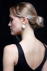 Female in black t-shirt with bun hairdo. Back view portrait of young blonde woman.