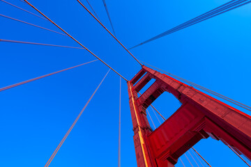 Tall red main tower of iconic Golden Gate Bridge seen from the bridge deck. Major tourist...
