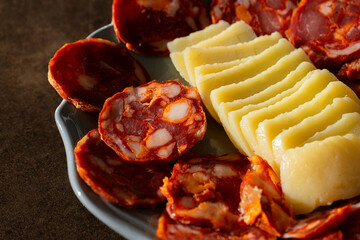 A traditional Alentejo sausage, known as paio, sliced and displayed alongside a rustic cheese wheel...