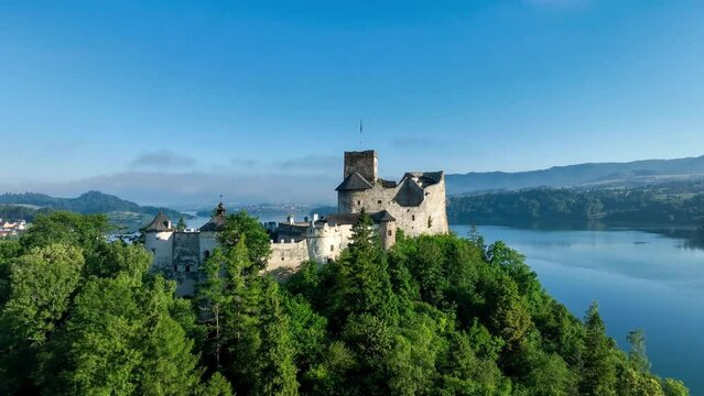 Poland. Medieval Castle in Niedzica, 14th century (upper castle). The ownership of Polish State.  Artificial Czorsztyn dam lake. Aerial approaching video in the morning in sunrise light