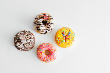 Assorted donuts with chocolate frosted, pink glazed and sprinkles donuts isolated on white...