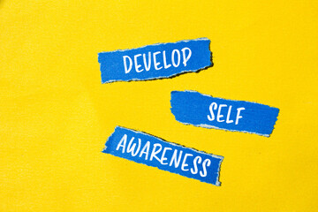 Develop self awareness words written on ripped blue paper pieces with yellow background. Conceptual...
