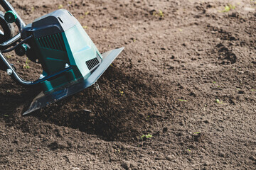 farmer prepares the soil for planting with electric cultivator