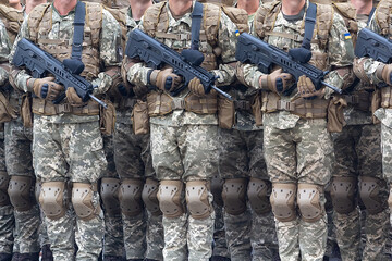 A line of soldiers in camouflage uniforms with a machine gun and insignia of the Ukrainian army