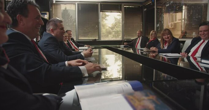 Senior businesspeople working together in a good atmosphere on a new big business project, analyzing stats, discussing details, having fun conversation. Multi-ethnic conference room.