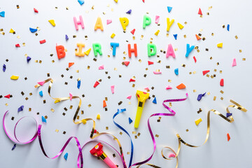Creative composition made with birthday party things and party streamers on white background....