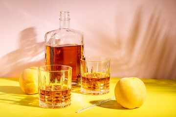 Alcoholic drink in a glass with a peach on a bright background. Summer party concept.