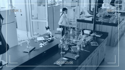 Full high angle CCTV camera shot of Asian female employee of research laboratory working alone - typing on laptop, then walking over to table and handling chemical liquids and reagents - Powered by Adobe