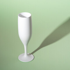 White champagne glass on green background. Minimal party concept.