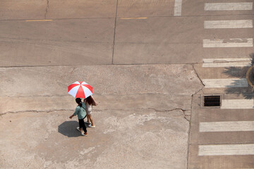In the hot sun, there were still people walking on the road with umbrellas.