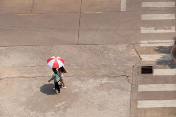 In the hot sun, there were still people walking on the road with umbrellas. © 2D_Jungle