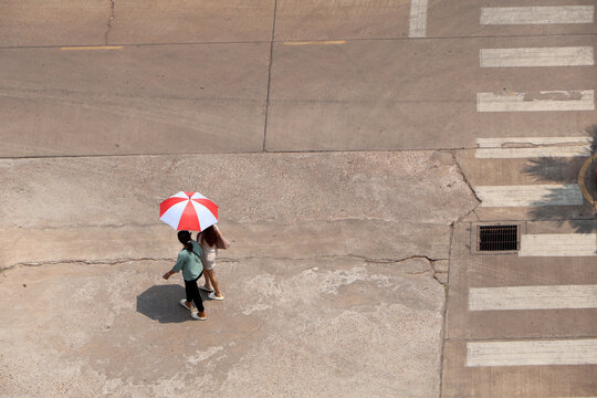 In the hot sun, there were still people walking on the road with umbrellas.