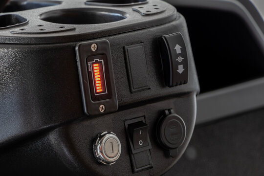 The car's dashboard has control buttons and lights showing the electric car's battery.