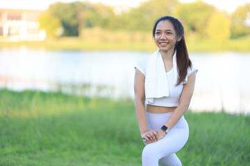 Beautiful Asian woman warms up and stretches before jogging in the park.