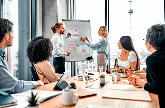 Statistics from analysts. Couple of accountants performing presentation in front of team of directors. Caucasian woman and man using diagrams for facilitating explanation of charts to audience.
