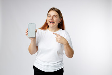 Great Mobile Offer. Excited happy 30s woman pointing finger at Smartphone in her hand over white background.